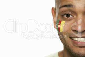 Young Male Sports Fan With Cameroon Flag Painted On Face
