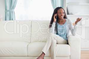 Woman talking on the phone while sitting on the sofa