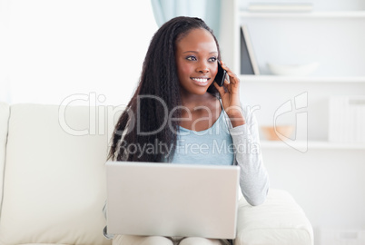 Woman with smartphone and laptop on the sofa