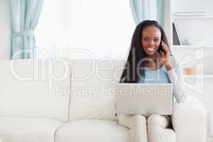 Woman with laptop and mobile phone on the sofa