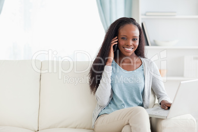 Woman with cellphone and notebook on the sofa