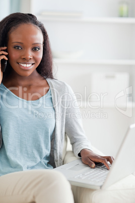 Close up of woman with cellphone and laptop on sofa