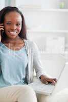 Close up of woman with cellphone and laptop on sofa