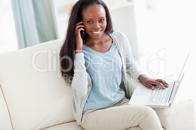 Woman on sofa with laptop and cellphone