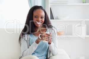 Woman with cup on sofa