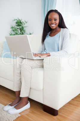 Woman on couch typing on her laptop