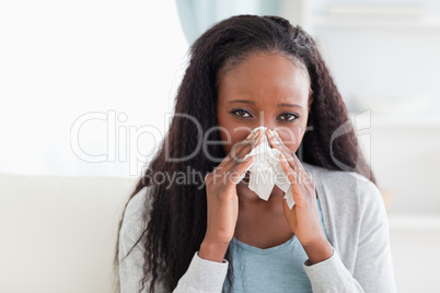 Close up of woman on sofa blowing her nose