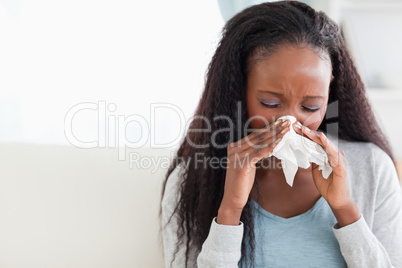 Close up of woman blowing her nose on couch