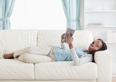 Woman lying on couch reading a book