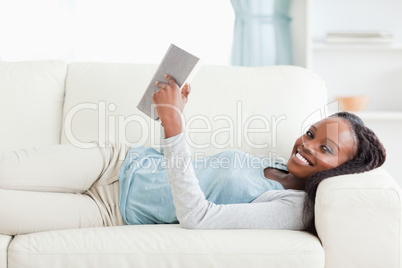 Woman lying on couch reading a novel