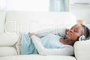 Woman listening to music while lying on sofa