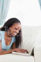 Close up of woman lying on the sofa working on her laptop