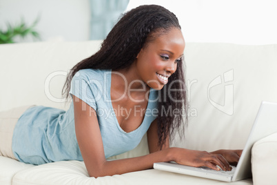 Woman lying on the couch working with her laptop