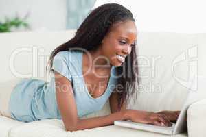 Woman lying on the couch working with her laptop