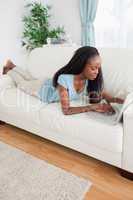 Woman lying on the sofa using her laptop
