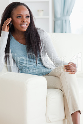 Woman sitting on sofa while using her mobile phone