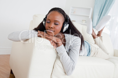 Woman with eyes closed enjoying music on her sofa
