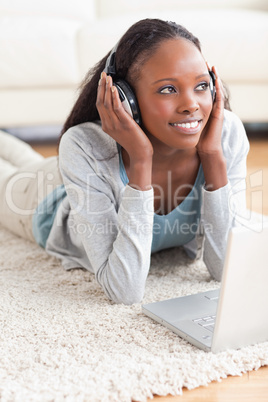 Close up of woman lying on the floor with her notebook listening