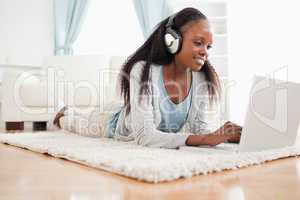 Woman lying on the floor with her laptop enjoying music
