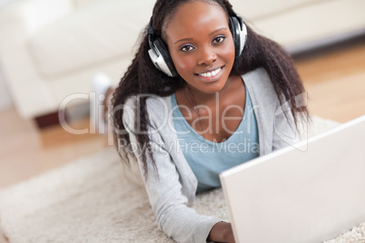 Close up of woman lying on the floor with her laptop enjoying mu