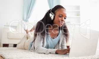 Woman lying on the floor with her notebook enjoying music