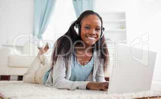 Woman lying on floor with her laptop listening to music