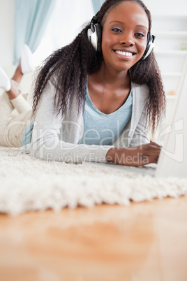 Close up of woman lying on floor with her laptop listening to mu