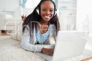 Woman lying on floor with her laptop enjoying music