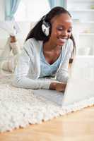 Close up of woman lying on floor with her laptop enjoying music