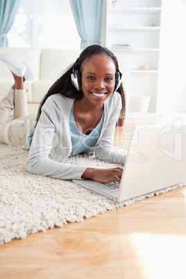 Close up of woman lying on the floor with laptop listening to mu