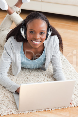 Close up of woman lying on the floor with notebook listening to