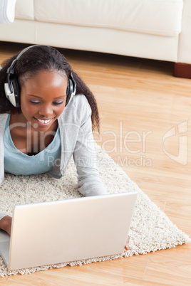 Close up of woman lying on floor with laptop listening to music