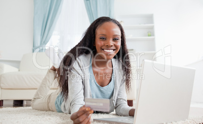 Woman lying on the floor with her laptop shopping online