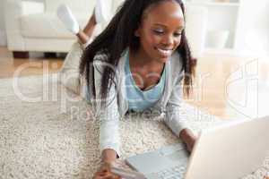 Close up of woman lying on the floor with her laptop shopping on