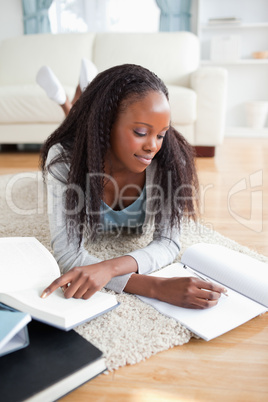 Woman lying on carpet doing her homework