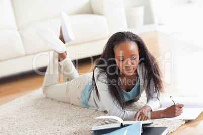 Woman lying on carpet doing a book review