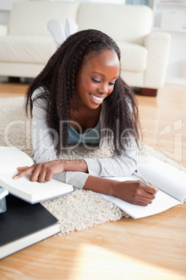 Young woman lying on the floor doing her homework
