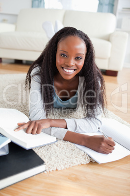 Young woman lying on carpet doing a book review