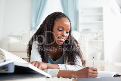 Woman lying on the carpet taking notes