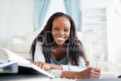 Woman lying on the carpet doing homework