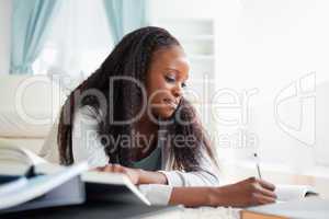 Woman lying on carpet in living room studying