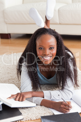 Woman lying on carpet in living room doing a book review