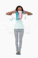 Woman hiding behind her shopping on white background