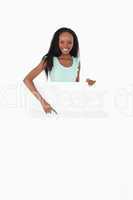 Woman pointing on placeholder below her on white background