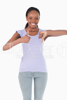 Close up of woman giving one thumb up and one down on white back