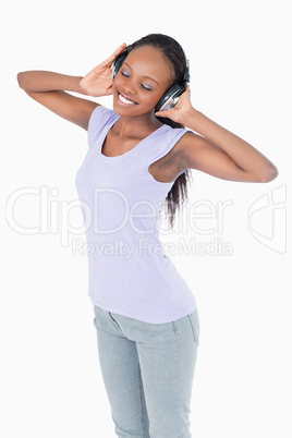 Close up of woman listening to music with headphones on white ba