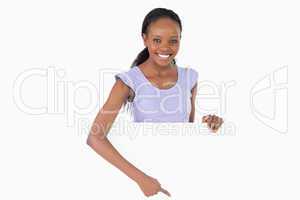 Woman pointing on placeholder beneath her on white background