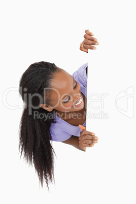 Young woman looking around the corner on white background