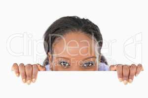 Woman taking a look above an edge on white background