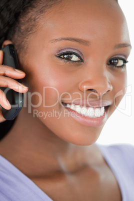 Close up of woman talking on the mobile phone against a white ba